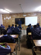 Mr Nyoni presents ABE in front of a classroom of seated learners from Ekangala Engineering School of Specialisation in Mining. 